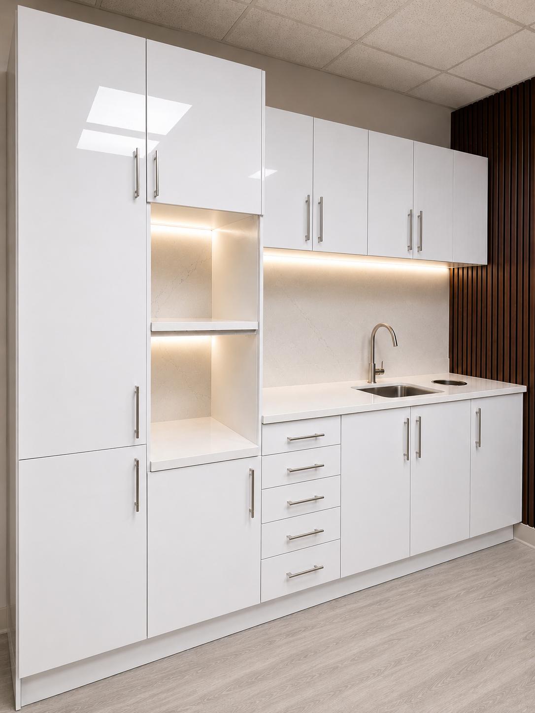 Gloss white dental sterilization center by DRM Dental with tall storage column, lit open shelving, quartz countertop, sink, and drawer bank